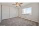 This cozy bedroom features neutral carpet, a ceiling fan, a large window, and a spacious closet at 745 N Royal Crest Cir # 157, Las Vegas, NV 89169