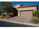 Attractive single-story home with desert landscaping, a brick driveway, and a two-car garage at 832 Gallery Course Dr, Las Vegas, NV 89148