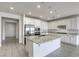 Open-concept kitchen features an island, white cabinets, stainless steel appliances, and light gray wood-look tile flooring at 832 Gallery Course Dr, Las Vegas, NV 89148
