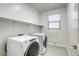 This is a laundry room with light gray wood-look tile flooring, shelving, and a front-load washer and dryer at 832 Gallery Course Dr, Las Vegas, NV 89148