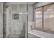 Modern bathroom featuring a glass-enclosed shower, tiled walls, and a window above the bathtub at 8517 Soneto Ln, Las Vegas, NV 89117