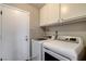 A laundry room featuring a white washer and dryer set with upper cabinet storage and a white door at 8517 Soneto Ln, Las Vegas, NV 89117