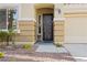 Close up of front entrance with detailed front door, small garden, and two-car garage at 9256 Blue Flax Pl, Las Vegas, NV 89148