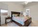 Warm bedroom featuring a floral comforter, carpeted floor and a peek into a bathroom at 9256 Blue Flax Pl, Las Vegas, NV 89148