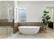 This airy bathroom features a glass-enclosed shower, a standalone tub, and sleek tiling at 9408 Players Canyon Ct, Las Vegas, NV 89144