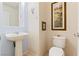 Powder room featuring a pedestal sink, toilet, and decorative artwork on the walls at 10478 Beallsville St, Las Vegas, NV 89141