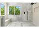 Modern walk-in shower with gray tiled walls, black fixtures, a built-in bench, and a window with natural light at 2105 Madagascar Ln, Las Vegas, NV 89117