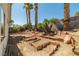 Expansive backyard featuring unique rock landscaping and mature palm trees, offering a serene outdoor space at 3414 Drescina Way, North Las Vegas, NV 89031