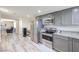 Well-lit kitchen with stainless steel refrigerator, range, and granite countertops with gray cabinets at 5093 Sun Valley Dr, Las Vegas, NV 89122