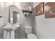 Charming powder room featuring a pedestal sink, decorative mirror, and modern fixtures at 6307 Dusty Mile Ct, North Las Vegas, NV 89031
