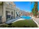Inviting backyard featuring a refreshing pool, covered patio, and artificial turf, perfect for outdoor entertaining and relaxation at 7537 Splashing Rock Dr, Las Vegas, NV 89131
