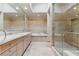 This is a bathroom featuring double sinks, marble countertop and tile flooring, a bathtub, and a glass-enclosed shower at 8215 Crow Valley Ln, Las Vegas, NV 89113