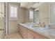 Bathroom features dual sinks, light wood cabinetry, marble countertops, and shuttered windows at 8215 Crow Valley Ln, Las Vegas, NV 89113