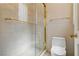 Bathroom featuring a glass-enclosed shower with gold fixtures and tile walls, complemented by a modern toilet at 8215 Crow Valley Ln, Las Vegas, NV 89113