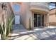 Elegant entrance features a white door, desert landscaping, and a covered patio with seating at 8215 Crow Valley Ln, Las Vegas, NV 89113