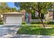 Inviting front of home with a two-car garage, green lawn, and mature trees at 8215 Crow Valley Ln, Las Vegas, NV 89113