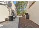 Side yard featuring brick pathway, utilities, and mature trees for added privacy at 8215 Crow Valley Ln, Las Vegas, NV 89113