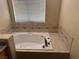 Bathroom featuring a large soaking tub with tiled surround and tile accents at 8225 Bermuda Beach Dr, Las Vegas, NV 89128