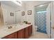 Bright bathroom with a wood vanity, large mirror, and blue patterned shower curtain at 8550 Little Fox St, Las Vegas, NV 89123