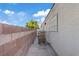 Narrow side yard with stone pavers and a block wall under a bright blue sky at 8550 Little Fox St, Las Vegas, NV 89123