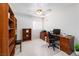 Well-lit home office with wooden bookshelves, a desk setup, and a ceiling fan for added comfort at 9604 Summer Cypress St, Las Vegas, NV 89123