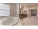 Bathroom with a tub next to a window, double vanity, and tile floors at 9876 Parador Cellars Ct, Las Vegas, NV 89141