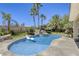 Inviting pool area with a unique rock waterfall, surrounded by lush greenery and mature palm trees at 9905 Fox Springs Dr, Las Vegas, NV 89117