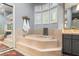Elegant bathroom with a step-up soaking tub, custom tile work, and plantation shuttered windows at 1 Dry Brook Trl, Henderson, NV 89052