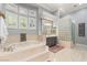 Spa-like bathroom featuring a jetted tub, glass block shower, and custom lighting fixtures at 1 Dry Brook Trl, Henderson, NV 89052