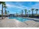 A community pool features tile surround, many palm trees, and lounge chairs with umbrellas at 12112 Polar White Ct # 3, Las Vegas, NV 89183
