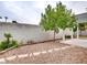 Backyard featuring white pergola, mature tree, a rock landscape area, and privacy wall at 2705 Chokecherry Ave, Henderson, NV 89074