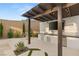 Outdoor kitchen with grill, TV, and bar area under a pergola in backyard at 389 Red Feather Peak Ct, Las Vegas, NV 89138