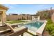 Backyard oasis featuring a pool, outdoor kitchen, artificial grass, and sun loungers at 389 Red Feather Peak Ct, Las Vegas, NV 89138