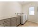 Bright laundry room with white washer and dryer, gray cabinets, and tile floors at 5735 Oak Bend Dr, Las Vegas, NV 89135