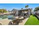Relaxing backyard has a sparkling pool, spa, outdoor seating, and dining set surrounded by lush grass and shady palm trees at 7026 Westpark Ct, Las Vegas, NV 89147