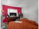 Cozy bedroom featuring a red accent wall, window, television, and a warm, inviting atmosphere at 7026 Westpark Ct, Las Vegas, NV 89147