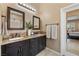 Bathroom featuring dual sinks, granite countertops, dark cabinets, and an adjacent walk-in shower at 7914 Elk Mountain St, Las Vegas, NV 89113
