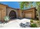 Attractive front entrance showcasing a stone-arch doorway, a quaint desert garden, and a tan-colored garage door at 7914 Elk Mountain St, Las Vegas, NV 89113