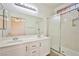 Bathroom with dual sinks, white cabinets, shower and bath stall with a clear glass door at 7929 Palace Monaco Ave, Las Vegas, NV 89117