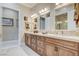 Elegant bathroom featuring double sinks, a marble countertop, and wood cabinets at 8574 Verde Park Cir, Las Vegas, NV 89129