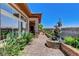Paver patio featuring a dolphin statue and lush landscaping along the house with large windows at 8574 Verde Park Cir, Las Vegas, NV 89129