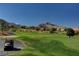 Expansive golf course with lush green grass, mountain views, and a golf cart on a sunny day at 9912 Woodhouse Dr, Las Vegas, NV 89134