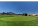 Scenic golf course with a blue flag on the green, set against a backdrop of mountains and clear blue sky at 9912 Woodhouse Dr, Las Vegas, NV 89134
