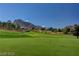 Well-maintained golf course green with a flag, surrounded by lush greenery and scenic mountain views at 9912 Woodhouse Dr, Las Vegas, NV 89134