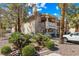 A bright, stucco-sided condo with desert landscaping and access stairs, surrounded by trees at 1001 Sulphur Springs Ln # 202, Las Vegas, NV 89128