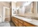 Bathroom with double sinks, granite countertops, and wooden cabinets, plus white tile floors at 10445 Schirlls St, Las Vegas, NV 89141