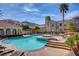 Inviting community pool area with lounging chairs, palm trees, and beautiful building views surrounded by lush foliage at 10550 W Alexander Rd # 2220, Las Vegas, NV 89129