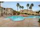 Inviting community pool area with lounging chairs, palm trees, and beautiful building views surrounded by lush foliage at 10550 W Alexander Rd # 2220, Las Vegas, NV 89129