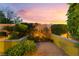 Private backyard with lush greenery, manicured hedges, and a colorful sky at dusk, offering a serene outdoor retreat at 12276 Caminita Pl, Las Vegas, NV 89138