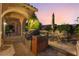 A dusk view of the backyard patio with an outdoor dining set and outdoor kitchen for entertaining at 12276 Caminita Pl, Las Vegas, NV 89138